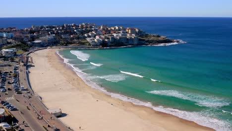 Calm-Waves-Onto-Shore-With-Cars-Park-Near-Sandy-Beachfront-Of-Bondi-Beach-In-Sydney,-New-South-Wales,-Australia