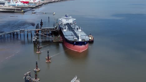 Crude-oil-tanker-ship-loading-at-refinery-harbour-terminal-aerial-reverse-view
