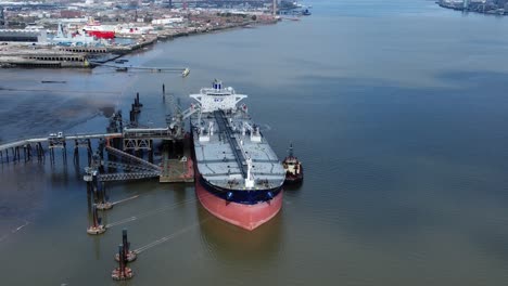 Crude-oil-tanker-ship-loading-at-refinery-harbour-terminal-aerial-view-dolly-left-reverse