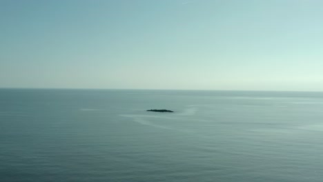 Birds-eye-view-of-single-rock-island-in-middle-of-nowhere-at-ocean