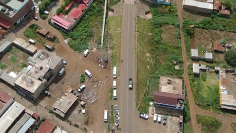 Aerial-view-following-a-truck-driving-through-a-small-town,-in-rural-Africa---top-down,-drone-shot
