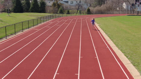 Teen-girl-on-a-track-breaks-into-a-run-towards-and-past-camera-on-a-pretty-day