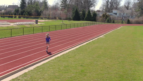 Teen-girl-on-a-track-running-by-and-away-from-camera-on-a-pretty-day