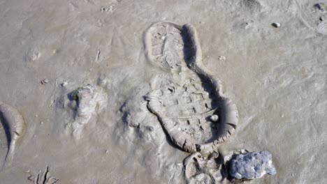 Muddy-sandy-wet-footprint-stamp-closeup-boot-detail-splattered-on-beach-track