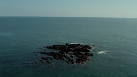 Drone-shot-of-orbiting-around-rocks-in-middle-of-ocean-at-day
