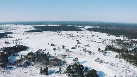 Aerial-View-of-Rural-Netherlands-on-Sunny-Winter-Day,-Snow-Capped-Land-and-Horizon-at-Radio-Kootwijk-Cathedral-on-Veluwe-National-park