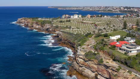 Waves-Crashing-On-Rocky-Cliffs-With-Waverley-Cemetery-At-Bronte,-Sydney,-NSW,-Australia