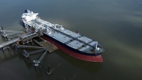 Crude-oil-tanker-ship-loading-at-refinery-harbour-terminal-aerial-view-zoom-in-to-deck