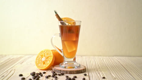 Ein-Glas-Eisgekühlter-Amerikanischer-Schwarzer-Kaffee-Und-Eine-Schicht-Aus-Orangen--Und-Zitronensaft,-Dekoriert-Mit-Rosmarin-Und-Zimt