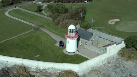 Drone-orbit-shot-above-lighthouse-at-sea-coast-in-summer,-wide-angle