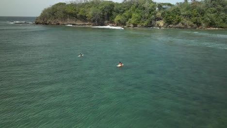 Drone-view-of-surfers-sitting-on-their-boards-while-in-the-waters-of-the-shallow-reef-of-Mt-Irvine,-Tobago