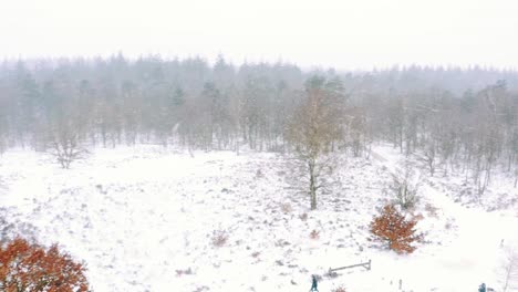 People-Walking-Through-A-Snowy-Forest-View-In-A-Winter-Storm---aerial-shot