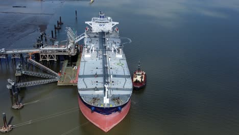 Crude-oil-tanker-ship-loading-at-refinery-harbour-terminal-aerial-view-pull-away-from-bow-tilt-up