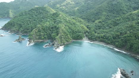 Erstaunliche-Luftaufnahme-Eines-Schwarzen-Sandstrandes-An-Der-Küste-Mit-Bergen-Als-Hintergrund-Auf-Der-Karibischen-Insel-Tobago