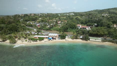 Descending-aerial-view-of-the-crystal-clear-waters-of-Mt-Irvine-Bay-on-the-tropical-Caribbean-island-of-Tobago