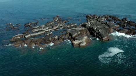 Beautiful-aerial-view-close-up-of-ocean-waves-at-rocks-at-sea-in-summer