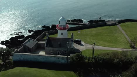 Aerial-orbit-shot-of-lighthouse-near-sea-coast-in-summer-day