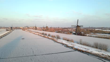 Golden-hour-sunlight-at-Kinderdijk-windmills-with-people-ice-skating-and-riding-bikes