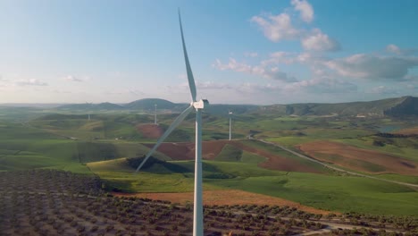 Aerial-view-of-Ardales,-south-of-Spain,-with-wind-turbines,-corn-and-olive-fields-at-daytime