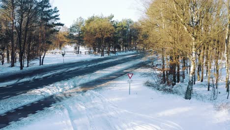 Carretera-Vacía-Bordeada-De-árboles-Cubierta-Parcialmente-De-Nieve,-Covid-Corona-Virus-Bloqueo-Vista-De-Drones