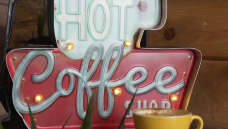 Heißes-Café-Schild-Und-Eine-Tasse-Kaffee-Auf-Dem-Display---Nahaufnahme