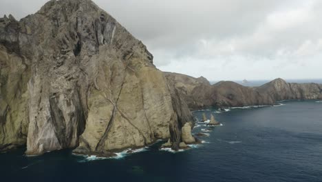 Wild-volcanic-coastline-of-Porto-Santo-on-cloudy-day-with-blue-ocean,-aerial