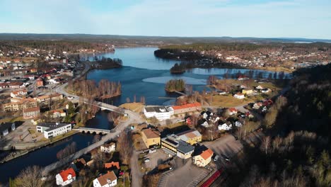 Aerial-flyover-rural-city-with-natural-blue-lake-during-golden-sunny-day