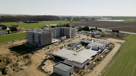 Aerial-view-showing-large-construction-area-build-apartment-blocks-in-rural-residential-area-during-sunlight