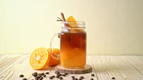 Ein-Glas-Eisgekühlter-Amerikanischer-Schwarzer-Kaffee-Und-Eine-Schicht-Aus-Orangen--Und-Zitronensaft,-Dekoriert-Mit-Rosmarin-Und-Zimt