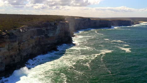 Waves-Crashing-Into-Rugged-Cliffs-At-Royal-National-Park-In-New-South-Wales,-Australia---aerial-drone-shot