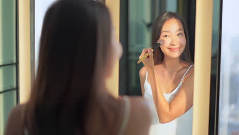 Bella-Mujer-Asiática-En-El-Espejo-Poniéndose-Maquillaje-Con-Un-Cepillo-Suave