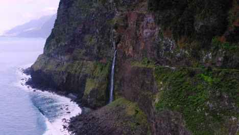 Madeira-Waterfall-in-Mountains-and-blue-ocean-in-backdrop-during-sunny-day-on-island,-Portugal,-Aerial-towards-flight