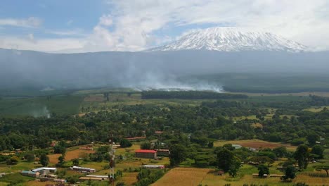 Aerial-drone-view-of-smoking-forest-and-fields-on-fire,-burning-East-African-countryside