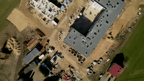Multistoried-building-construction-site-in-Lubawa,-Poland-drone-slowly-flying-forward-showing-construction-progress-from-top-view