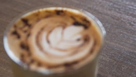 Café-Latte-Arte-En-Vidrio-Sobre-Una-Mesa-De-Madera---Primer-Plano