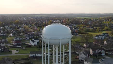 Aerial-vertigo-shot-of-water-tower,-revealing-suburban-neighborhood-in-the-background