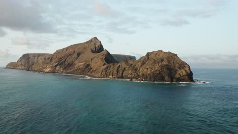 Amazing-volcanic-island-surrounded-by-blue-ocean-water,-Ilhéu-da-Cal
