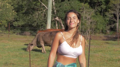 Sexy-Caucasian-Woman-Looking-At-Cows-Eating-On-Pasture-Turn-Around-And-Smile-At-Camera---Rural-Farm-At-Currumbin-Valley,-QLD,-Australia