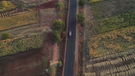 drone-following-Inova-car-from-top-in-rural-village-farm-road-cinematic-in-sunset-sunrise-Maharashtra-India-osmanabad-India-ter