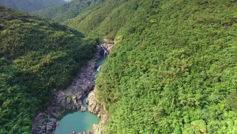 Aerial-reveal-of-beautiful-hidden-waterfall-between-mountain-hill-valley