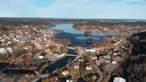 Aerial-view-of-small-swedish-city-with-natural-blue-lake,-bridges-and-buildings-during-summer