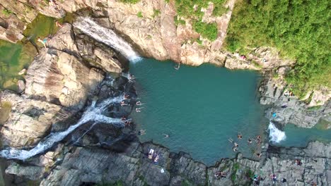People-relaxing-during-summer-holiday-recreation,-Sai-Kung-Rock-Pool-waterfalls-and-fresh-blue-water,-Hong-kong,-static-4K-aerial-view