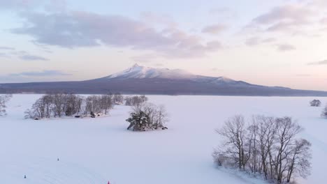Drone-slowly-pulling-back-from-beautiful-snowy-landscape-over-frozen-lake