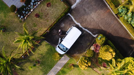 Aerial-view-above-friends-getting-in-a-parked-car--top-down,-drone-shot