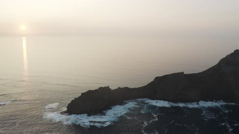 Silhouette-of-Ilhéu-da-Cal-with-steep-rocky-cliffs-and-turbulent-waves