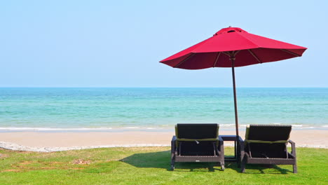 Ein-Paar-Leere-Strandbetten-Unter-Rotem-Sonnenschirm-Am-Majestätischen-Tropischen-Strand-An-Einem-Sonnigen-Tag,-Karibische-Urlaubslandschaft,-Vollbild
