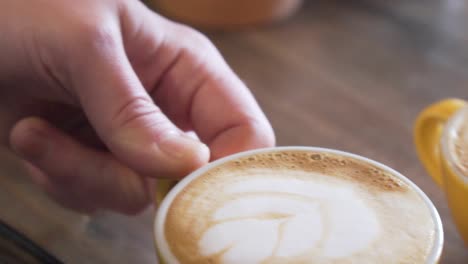 Hand-Serviert-Eine-Tasse-Cappuccino-Mit-Milchschaum-Latte-Art