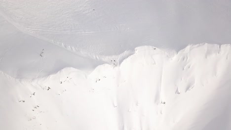 Vista-Superior-De-Un-Pico-De-Montaña-Nevado-Con-Figuras-Humanas-En-Movimiento