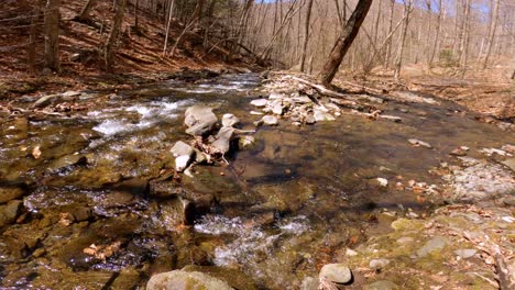A-beautiful-woodland-stream-during-early-spring,-after-snow-melt,-in-the-Appalachian-mountains-with-blowing-leaves