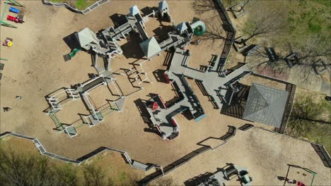 Descending-orbit-shot-of-children-on-playground-at-Liberty-Park-in-Clarksville,-Tennessee